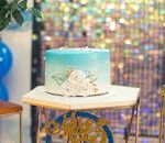 A blue gradient birthday cake with floral decorations on a festive table setup, perfect for celebrations.